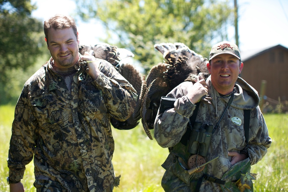 Two men with turkeys over their shoulders